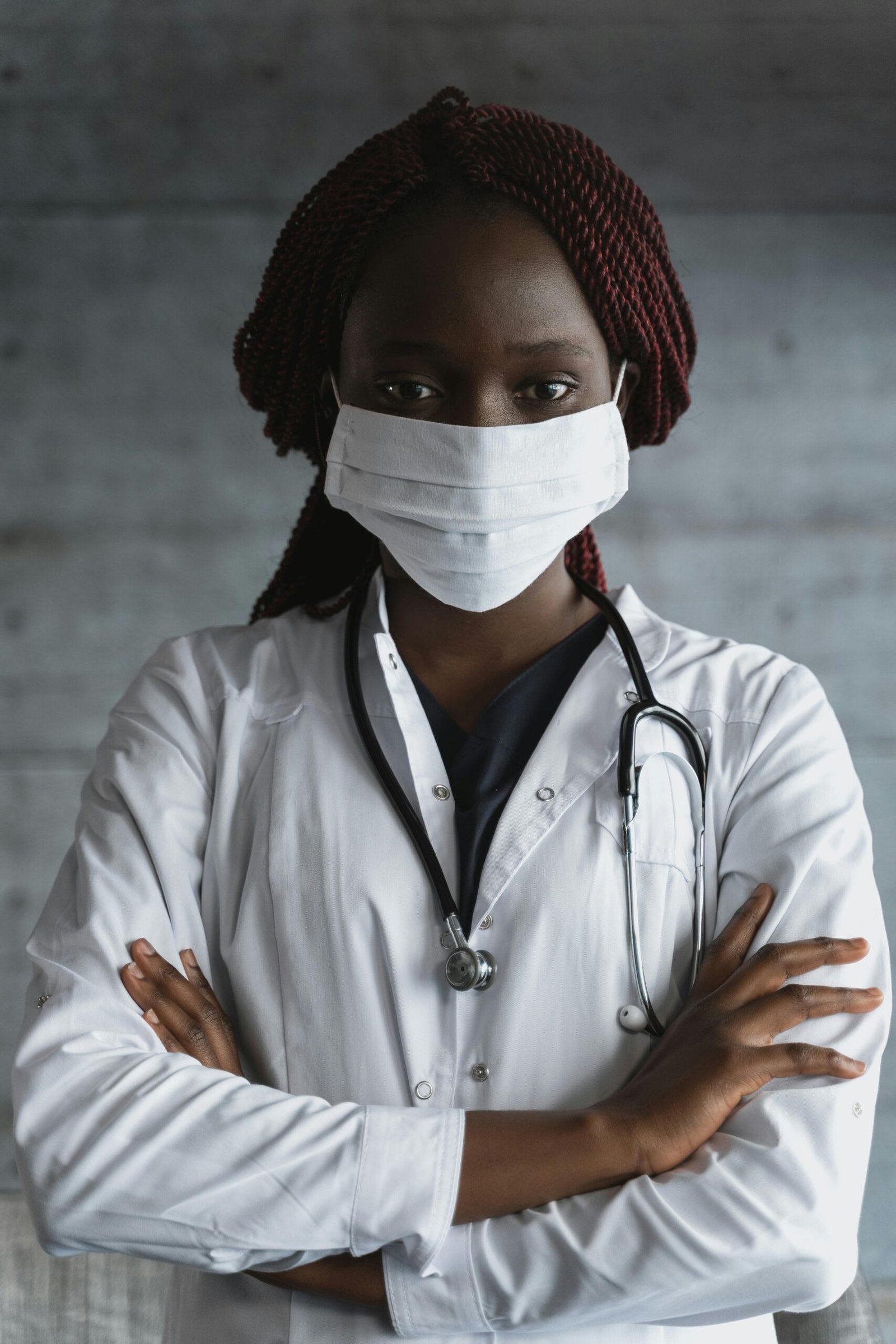 About Us Portrait of a confident female doctor wearing a mask and stethoscope, arms crossed.